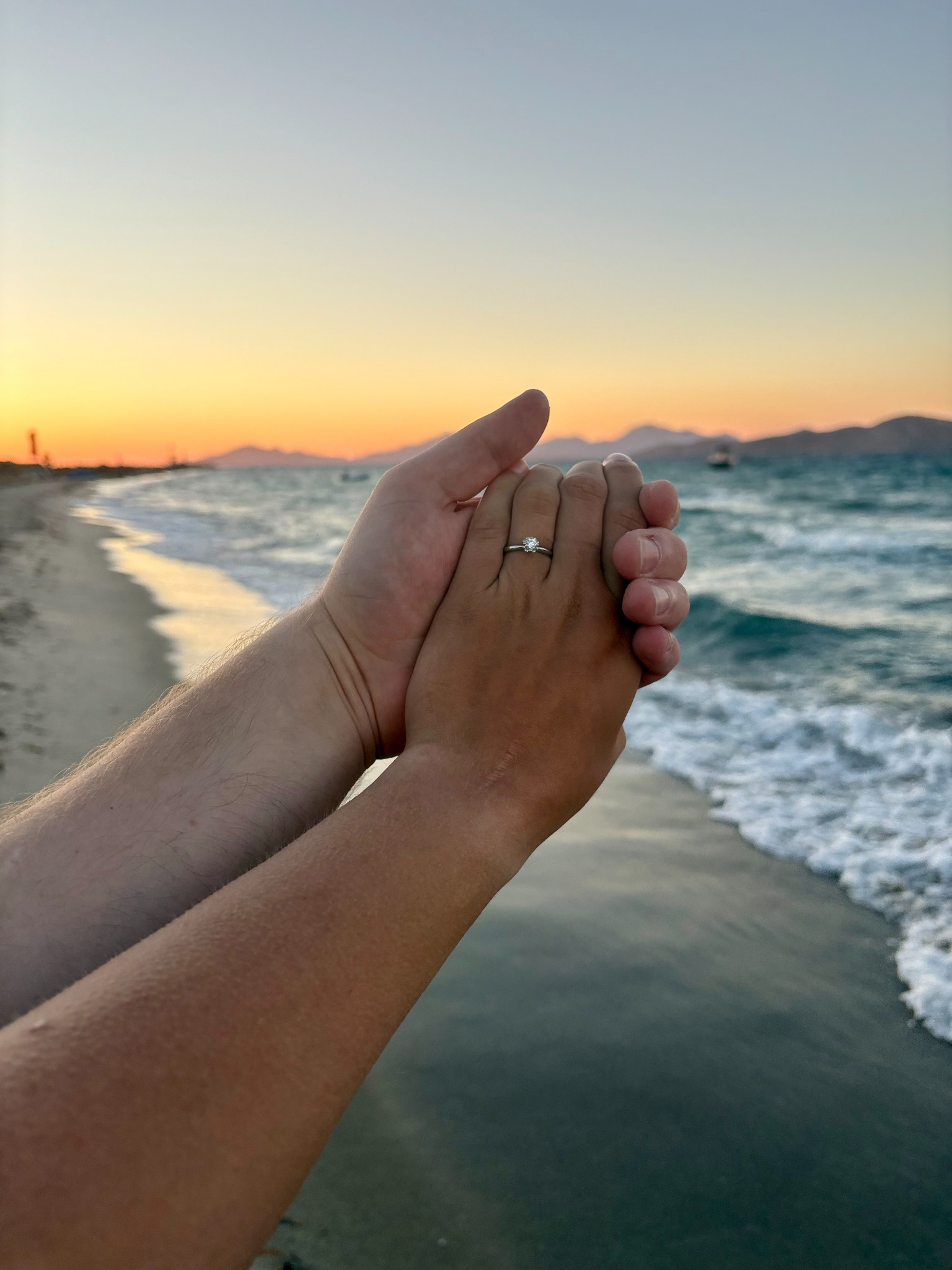 Hände mit Ring am Strand bei Sonnenuntergang